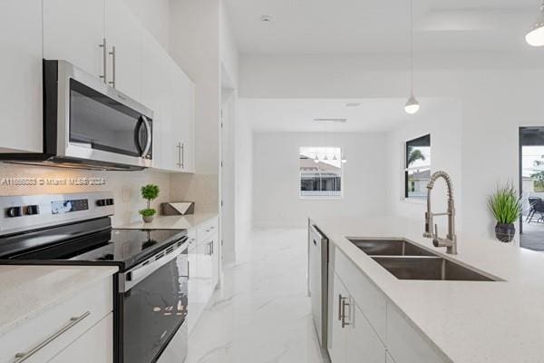 kitchen with white cabinetry, tasteful backsplash, pendant lighting, stainless steel appliances, and sink