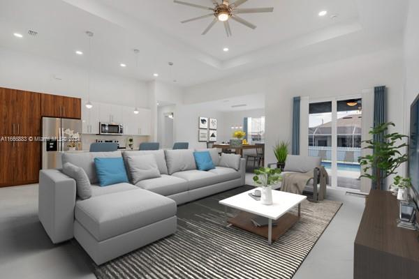 living room with a tray ceiling, a towering ceiling, and ceiling fan