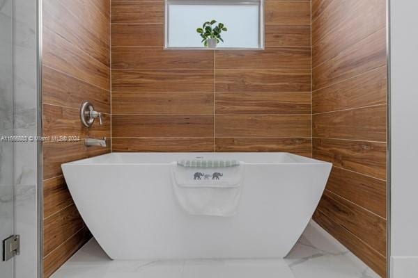 bathroom featuring wood walls and a bathtub