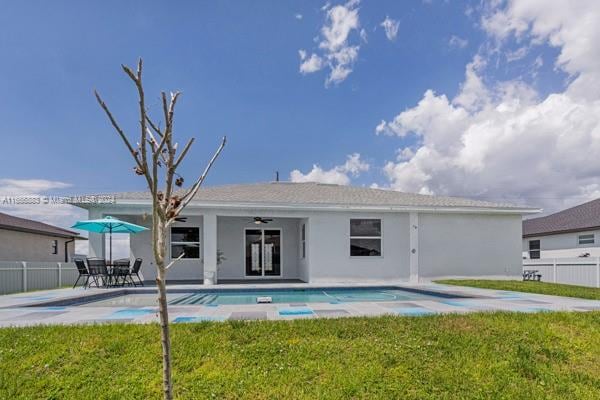 rear view of property featuring ceiling fan, a fenced in pool, a yard, and a patio area