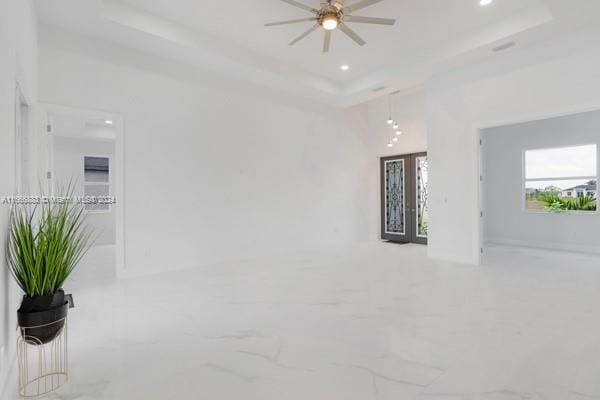 empty room featuring a tray ceiling and ceiling fan