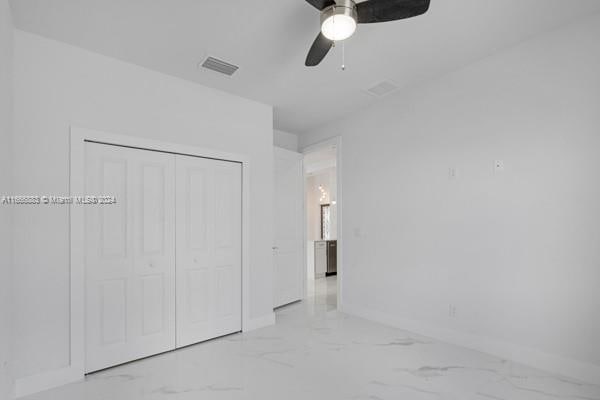 unfurnished bedroom with ceiling fan and a closet