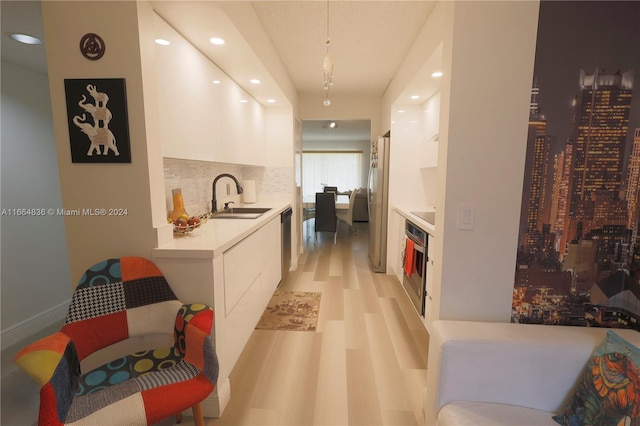 kitchen with appliances with stainless steel finishes, white cabinets, backsplash, pendant lighting, and sink