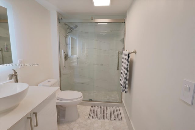 bathroom with vanity, toilet, and a shower with door