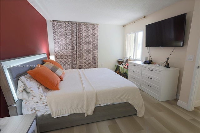 bedroom with a textured ceiling and light hardwood / wood-style flooring