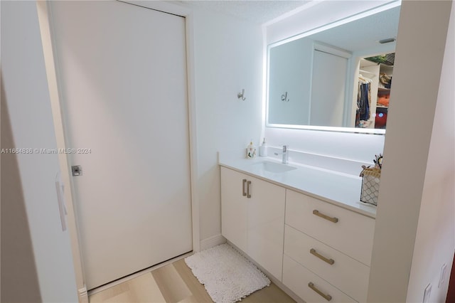 bathroom with a textured ceiling, hardwood / wood-style flooring, and vanity