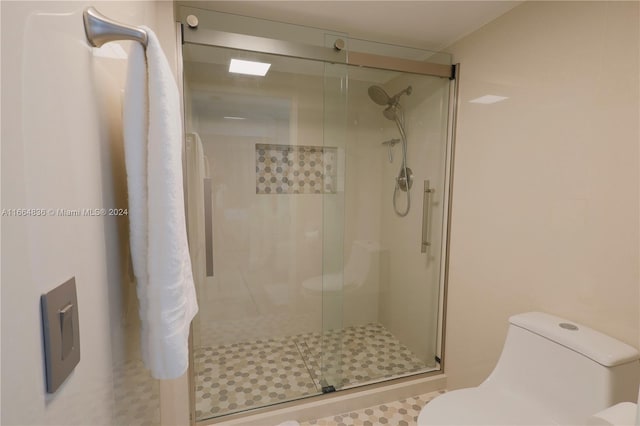 bathroom featuring a shower with door and toilet