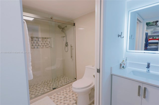 bathroom featuring tile patterned flooring, an enclosed shower, vanity, and toilet