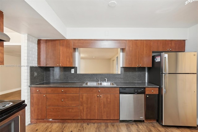 kitchen featuring sink, tasteful backsplash, appliances with stainless steel finishes, dark stone countertops, and light hardwood / wood-style floors