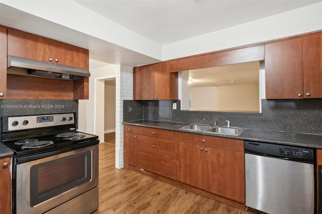 kitchen with light wood-type flooring, appliances with stainless steel finishes, tasteful backsplash, and sink