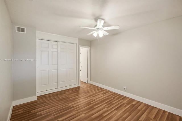 unfurnished bedroom featuring dark hardwood / wood-style flooring, ceiling fan, and a closet