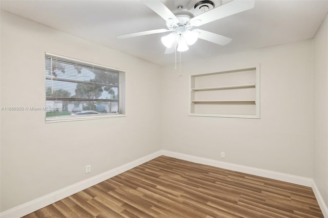 empty room with ceiling fan, built in features, and hardwood / wood-style floors