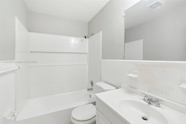 full bathroom featuring tile walls, vanity, tiled shower / bath, and toilet