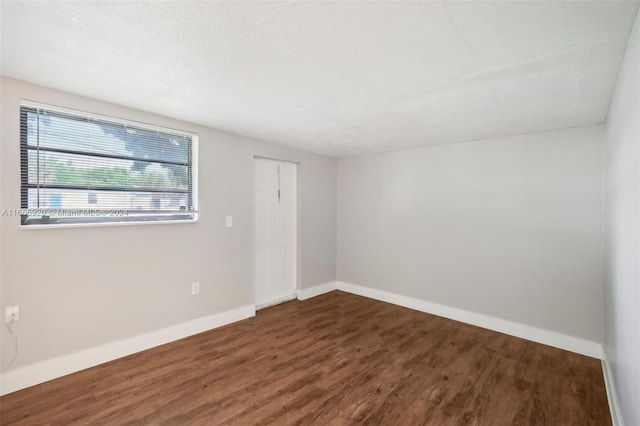 empty room with a textured ceiling and dark wood-type flooring