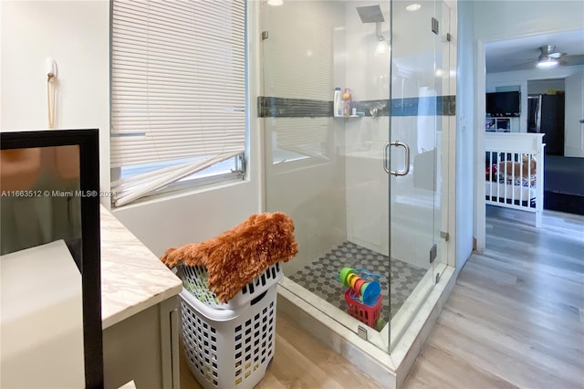 bathroom featuring wood-type flooring, ceiling fan, a shower with door, and vanity