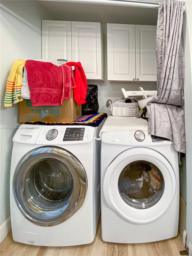 laundry area with cabinets, light hardwood / wood-style floors, and washer and dryer