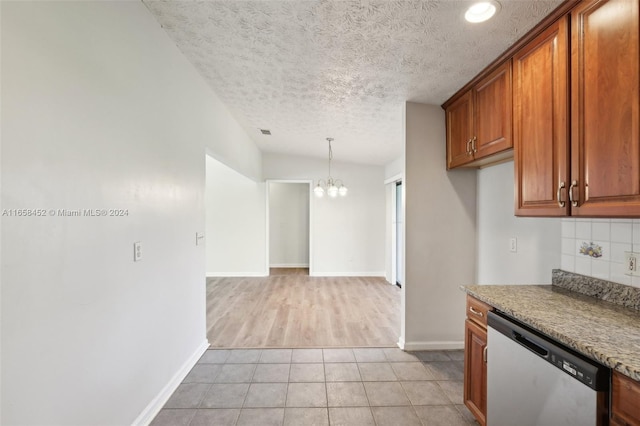 kitchen featuring light tile patterned floors, a textured ceiling, lofted ceiling, an inviting chandelier, and stainless steel dishwasher