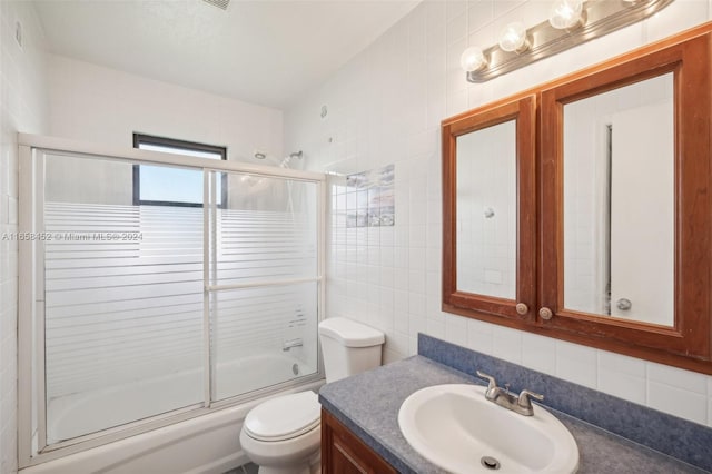 full bathroom featuring tile walls, combined bath / shower with glass door, decorative backsplash, vanity, and toilet