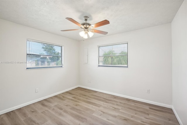 empty room with ceiling fan, hardwood / wood-style flooring, a textured ceiling, and a wealth of natural light