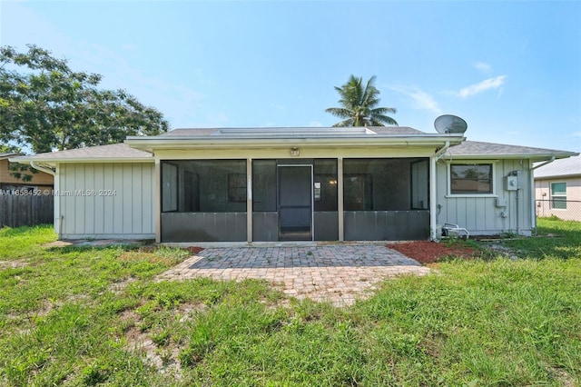 back of property with a sunroom, a patio, and a yard