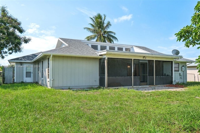 rear view of house with a sunroom and a yard