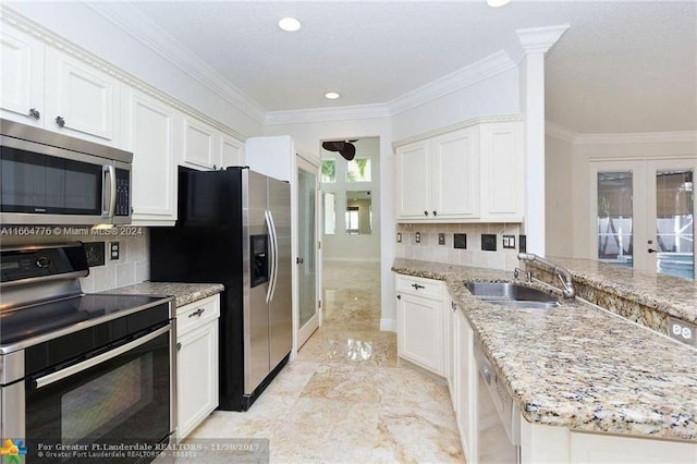 kitchen with sink, white cabinetry, stainless steel appliances, backsplash, and ornamental molding