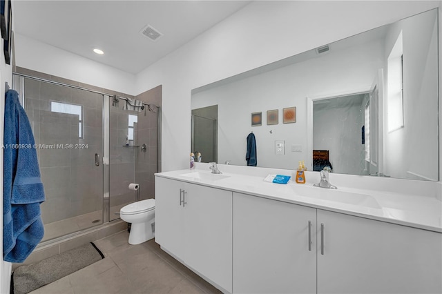 bathroom featuring tile patterned flooring, a shower with shower door, vanity, and toilet