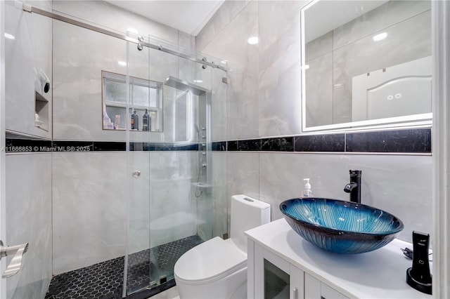 full bathroom featuring tile walls, a shower stall, toilet, and vanity