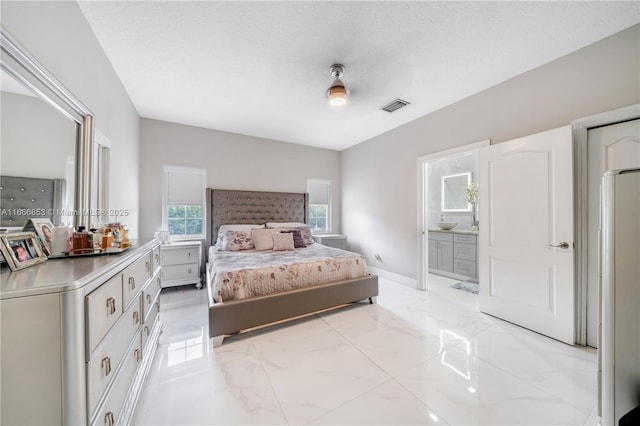 bedroom with baseboards, visible vents, ensuite bathroom, marble finish floor, and a textured ceiling