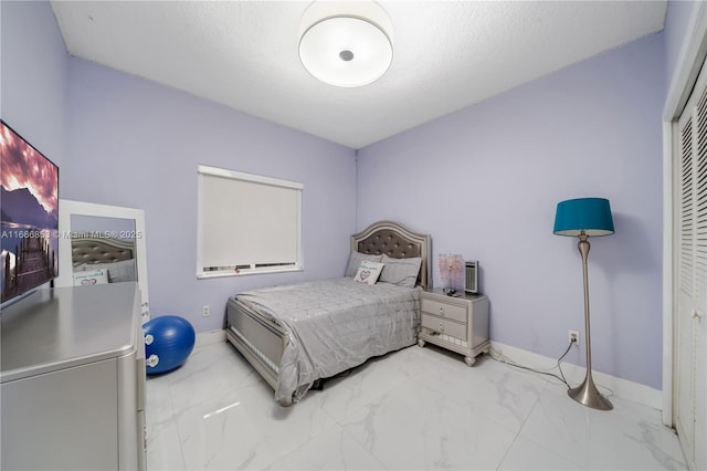 bedroom with a closet, marble finish floor, and baseboards