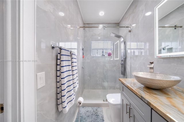 bathroom with toilet, vanity, tile walls, a shower stall, and decorative backsplash