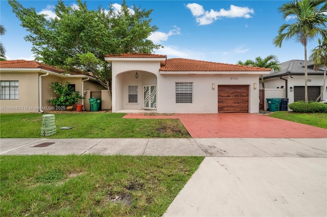 mediterranean / spanish-style house featuring an attached garage, concrete driveway, a tiled roof, stucco siding, and a front yard