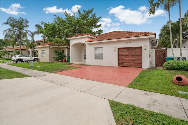 mediterranean / spanish home with an attached garage, concrete driveway, a tiled roof, stucco siding, and a front lawn