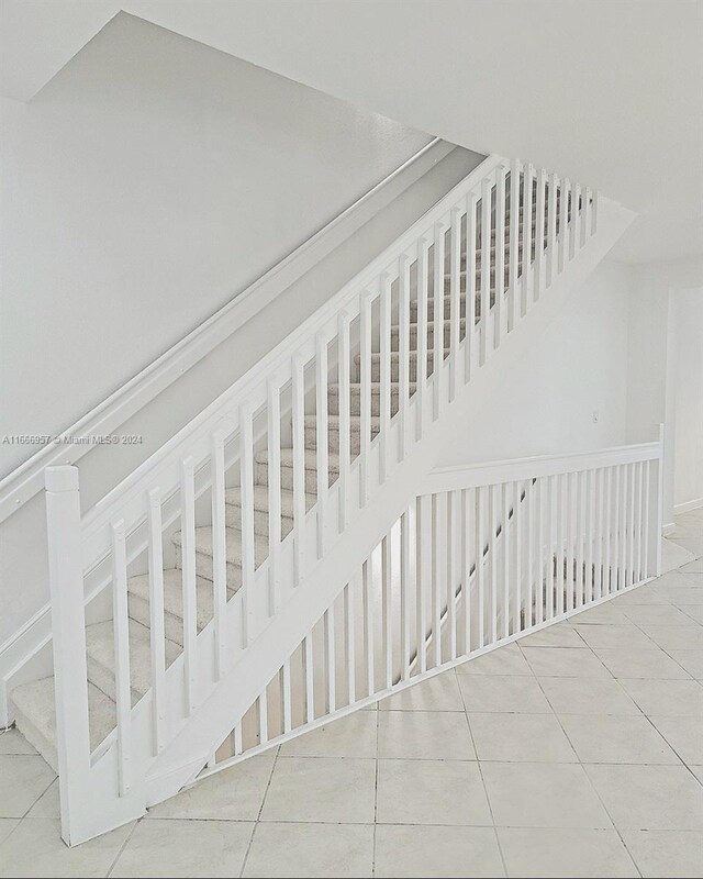 staircase with lofted ceiling and tile patterned flooring