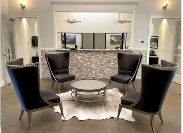 sitting room featuring ceiling fan and tile patterned flooring