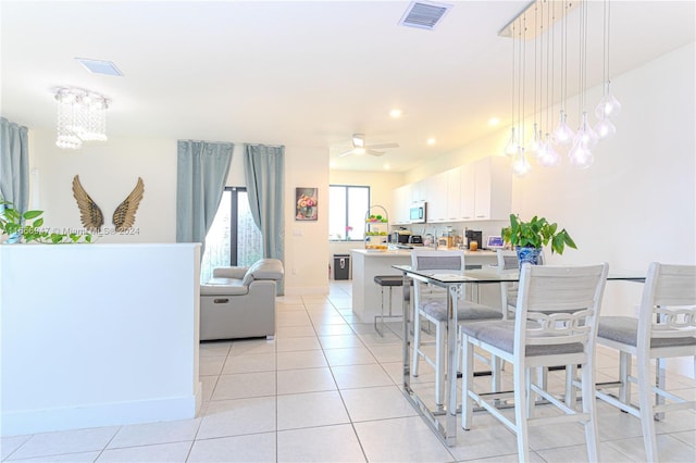 tiled dining space featuring ceiling fan with notable chandelier