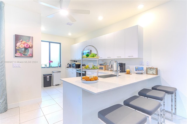 kitchen featuring kitchen peninsula, sink, a kitchen bar, and white cabinets