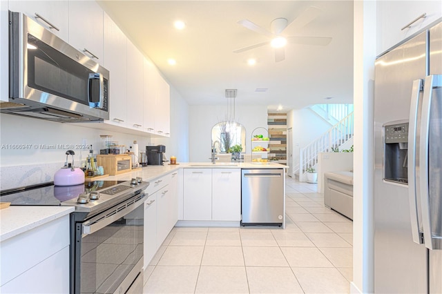 kitchen with white cabinets, hanging light fixtures, sink, kitchen peninsula, and stainless steel appliances