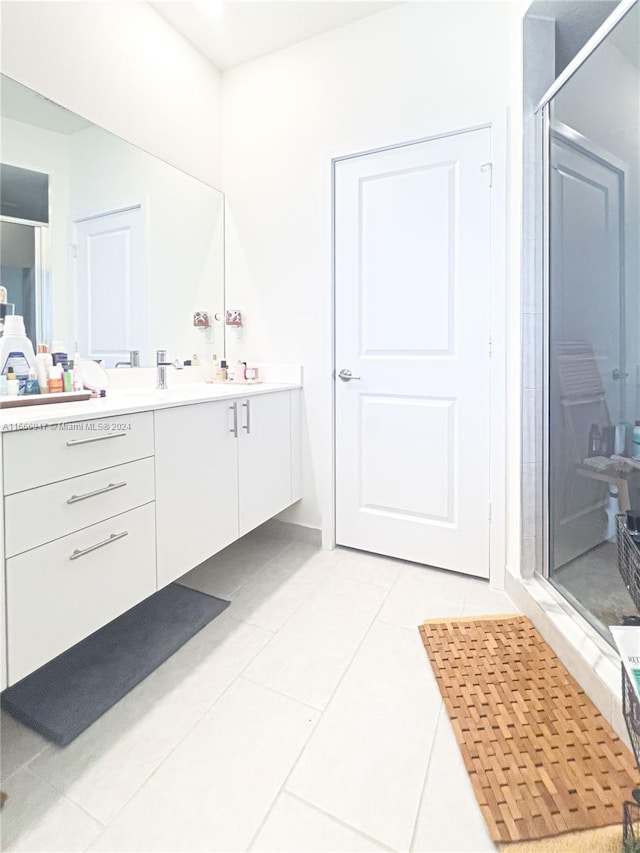 bathroom with tile patterned flooring, a shower with door, and vanity