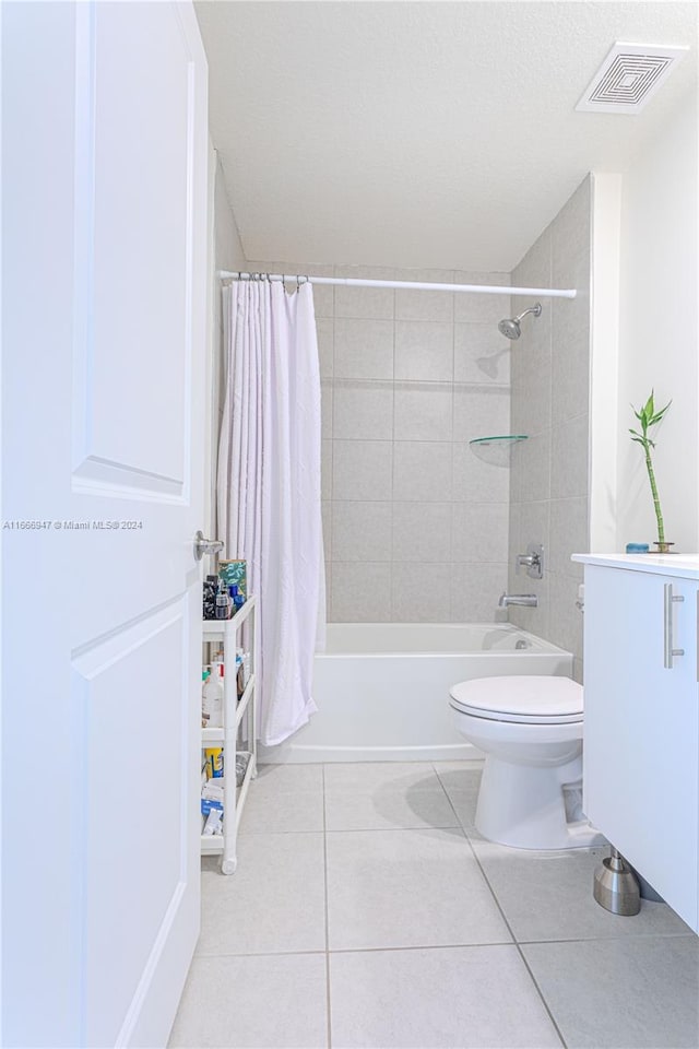 full bathroom featuring vanity, toilet, a textured ceiling, tile patterned flooring, and shower / tub combo with curtain