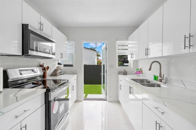 kitchen with light stone countertops, appliances with stainless steel finishes, sink, and white cabinetry