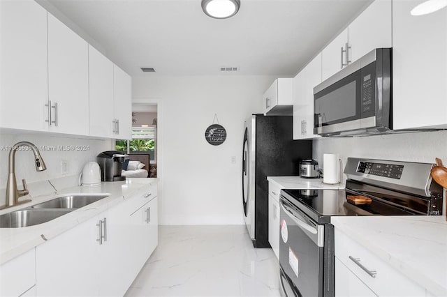 kitchen with light stone countertops, sink, stainless steel appliances, and white cabinets