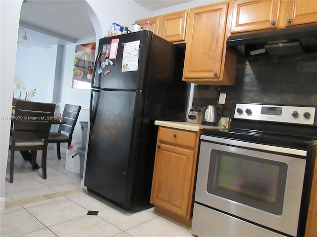 kitchen with ventilation hood, light tile patterned flooring, black refrigerator, and electric range