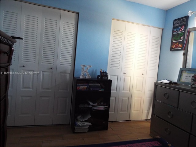 bedroom with hardwood / wood-style flooring and two closets