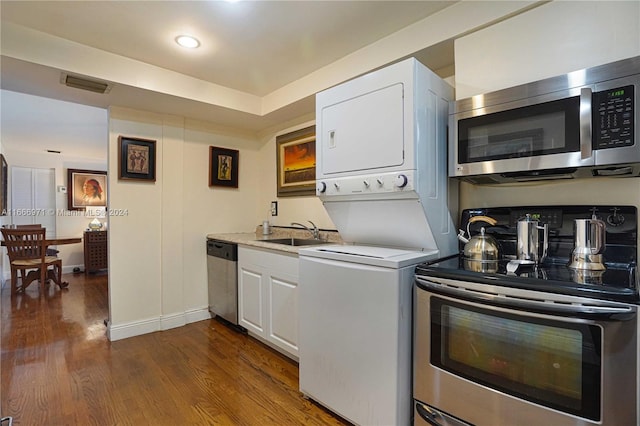 kitchen with dark wood-type flooring, sink, white cabinetry, stainless steel appliances, and stacked washer and clothes dryer