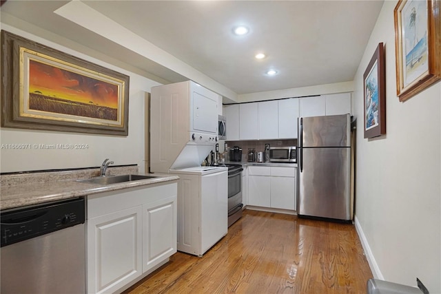 kitchen with white cabinets, appliances with stainless steel finishes, light wood-type flooring, and sink