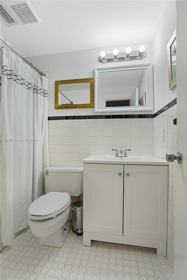 bathroom featuring tile walls, vanity, and toilet