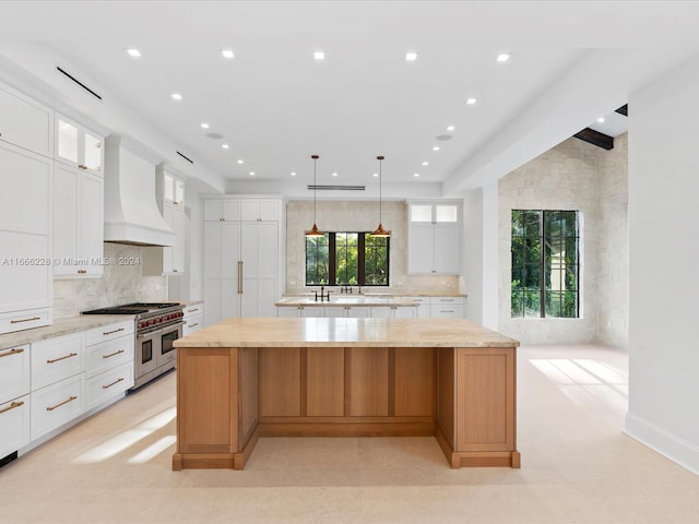 kitchen with custom exhaust hood, double oven range, a spacious island, and white cabinetry