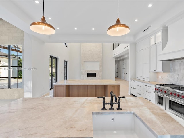 kitchen with white cabinets, range with two ovens, hanging light fixtures, and sink