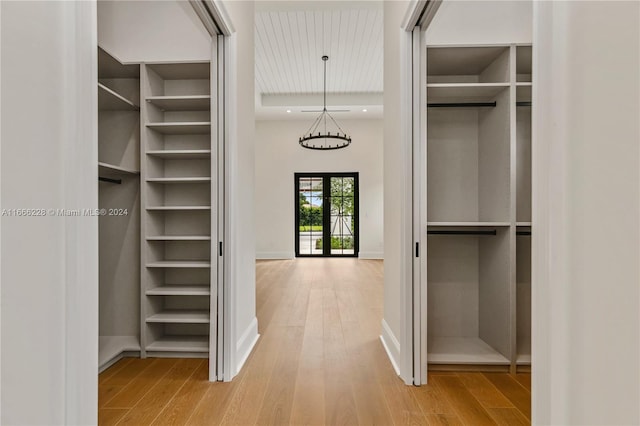 spacious closet featuring french doors, a chandelier, and hardwood / wood-style flooring